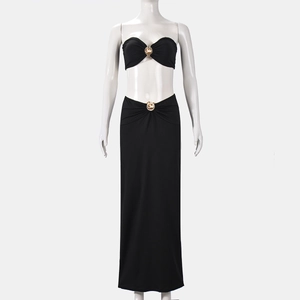 Detailed view of black two-piece set featuring gold metal buckles on top and long skirt