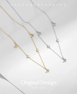 Macro detail of silver and gold butterfly necklaces with pave crystals and star-cut stones
