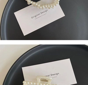 Detail of elegant pearl hair claw clip and elastic tie on a luxury black tray display