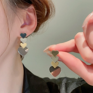 Detail of layered metal heart tassel earrings with silver and gold gradient finish