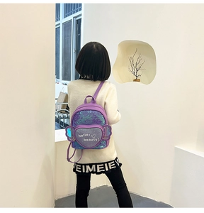 Girl wearing purple sequin backpack with heart pocket and decorative wings on the back