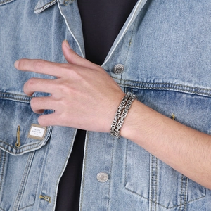 Close-up of dual-layer stainless steel Byzantine chain bracelet on denim fabric