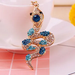 Macro detail of S-shaped snake keychain with blue crystals on a golden alloy base