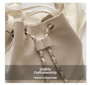 Detailed close-up of cream PU leather bucket bag with chain drawstring and metal eyelets
