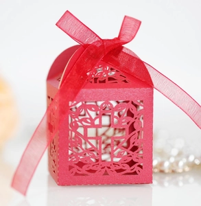 Close-up of red laser-cut candy box with cross pattern and elegant ribbon bow