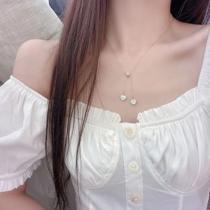 Detailed view of heart shell pendant necklace with tassel and zircon on a model's neck