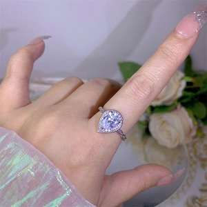 Close-up of sparkling pear-shaped zircon ring with halo setting on a silver metal band