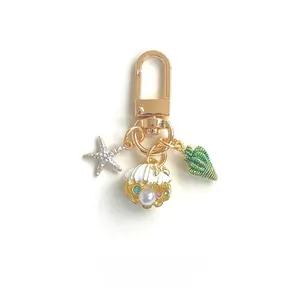 Detail of gold keychain with starfish, shell with pearls and green conch charms