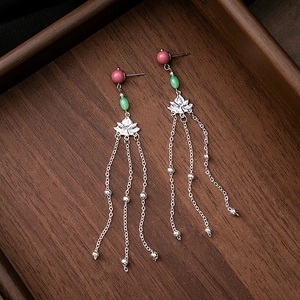 Close-up of floral metal plates with long silver chain tassels and colorful beads