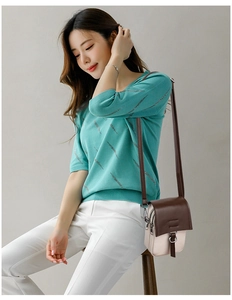 Detailed side view of a stylish two-tone crossbody bag worn by a model in casual attire