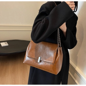 Detail of brown oil wax leather shoulder bag with silver square buckle and chain strap