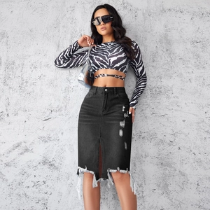 Detail of distressed black denim midi skirt featuring ripped accents and frayed tassel hem