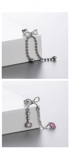 Macro detail of bow-shaped stud earrings with pink heart gemstone and key pendant charms
