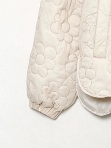 Detail of floral quilted pattern on cream jacket with elastic cuffs and stitching