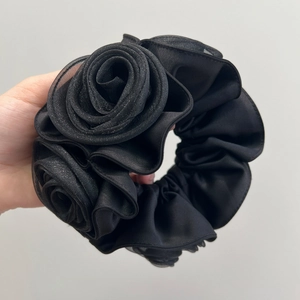 Detailed view of a black satin rose hair scrunchie featuring elegant double-layered petals