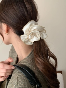 Détail du chouchou en satin beige élégant avec bordure dorée sur un chignon flou