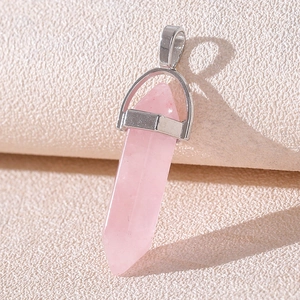 Close-up of hexagonal pink crystal column pendant with silver metal bail on beige paper