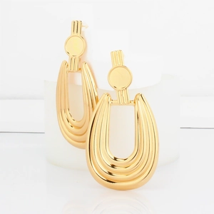 Detailed view of layered U-shaped gold geometric drop earrings on minimalist display