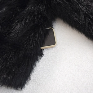 Detail of faux fur coat pocket with smartphone inside showing depth and texture