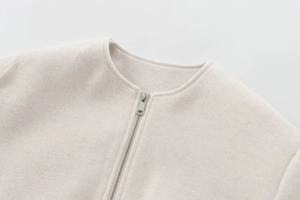 Gros plan détaillé de la veste en laine beige clair avec col rond et zip métallique