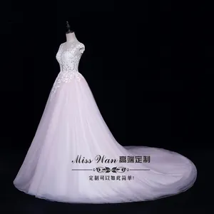 Détail du corsage en dentelle blanche et de la jupe en tulle rose d'une robe de mariée traîne