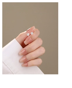 Detailed close-up of a model wearing minimalist silver five-petal flower stud earrings