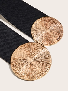 Macro shot of gold sunburst textured metal buckles on a black elastic wide belt