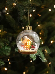 Detalle de bola de Navidad LED transparente con muñeco de nieve y casa interior