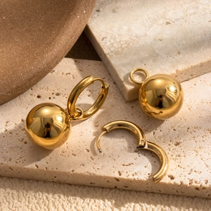 Elegant gold spherical earrings with rounded hoops displayed on textured stone