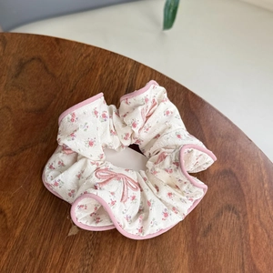 Detail of floral scrunchie with pink flowers and butterfly embroidery on a wooden table