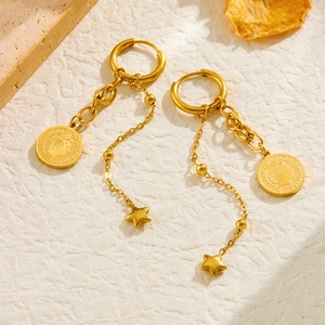 Detailed shot of gold earrings with vintage Elizabeth coin and star charms on textured paper