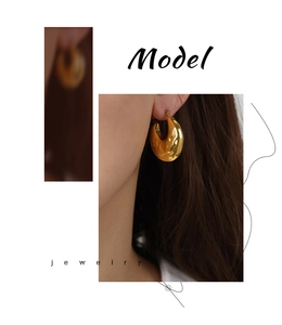 Detail shot of a model wearing textured gold-plated titanium steel hoop earrings