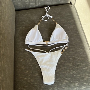 Detail of white seersucker bikini with gold metal chain straps and high cut side links