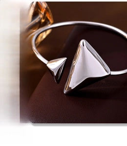 Close-up of silver stainless steel open bangle with polished triangle ends on leather