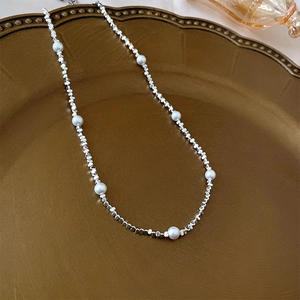 Close-up of silver cube beads and white pearls on an elegant vintage metal tray