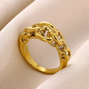 Macro shot of polished gold cuban link chain ring on beige velvet fabric background