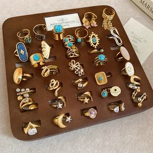 Macro detail of various boho rings featuring turquoise and crescent moon motifs on a tray