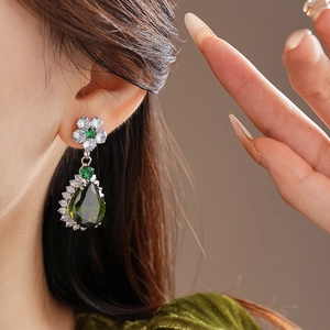 Close-up of leaf flower earrings with green teardrop zircon and white stone accents