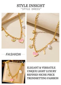 Detail of gold chain necklace with pink enamel heart, pearl, and Amour engraved charm