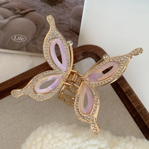 Detailed shot of rhinestone butterfly hair claw clip with purple resin and gold alloy frame