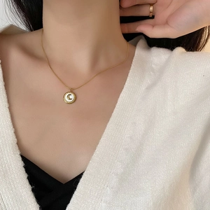 Collier en acier titane doré avec pendentif lune en nacre sur mannequin