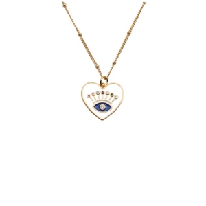 Macro detail of a gold heart pendant with a blue enamel evil eye and colorful zircon stones