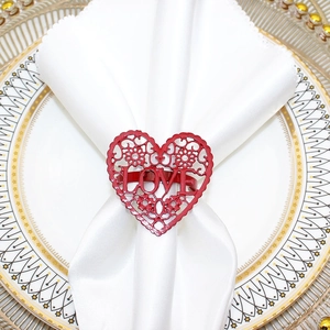 Close-up of red LOVE heart napkin ring with cut-out design on a white cloth napkin