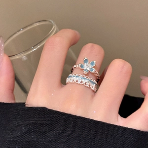 Detailed shot of light blue enamel flower ring set with silver lace cut-out style design