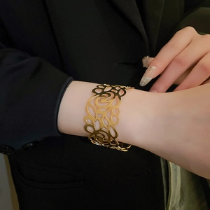 Macro detail of wide gold hollowed cuff bracelet featuring vintage filigree patterns