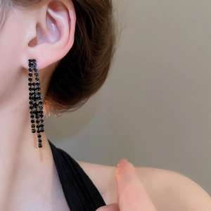Gros plan de boucles d'oreilles franges en cristal noir portées par un mannequin chic