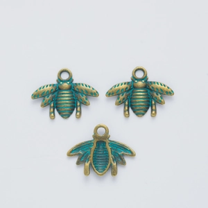 Detailed view of three vintage alloy bee pendants with bronze finish and teal enamel accents