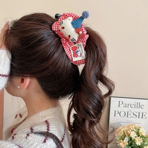 Detail of red plaid scrunchie with cute plush cat doll wearing blue party hat
