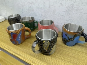 Group of stainless steel mineral crystal coffee mugs on a light wood shelf display