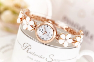 Detailed close-up of rose gold flower bracelet watch with crystal accents on a white mug